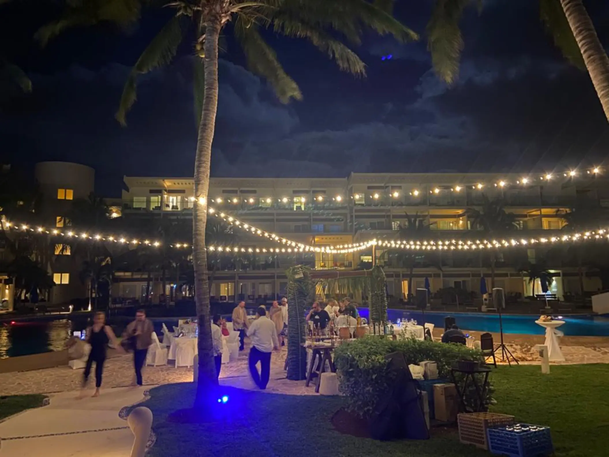 Outdoor wedding reception with string lights and guests by the pool at Iberostar Selection Riviera Cancun, Cancun