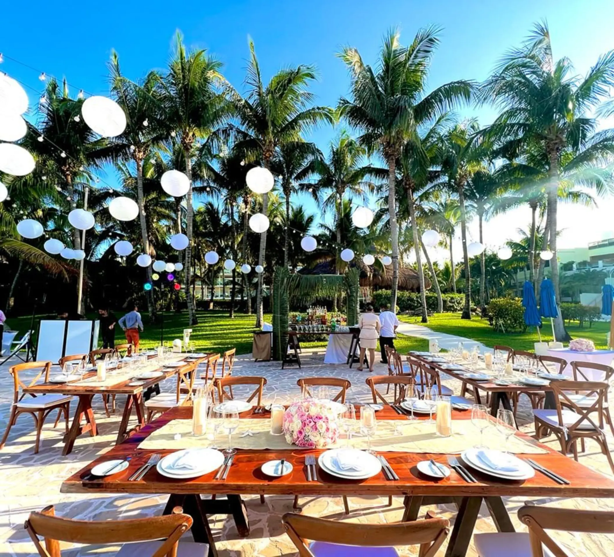 Outdoor wedding reception setup with wooden tables and white lanterns at Iberostar Selection Riviera Cancun, Cancun