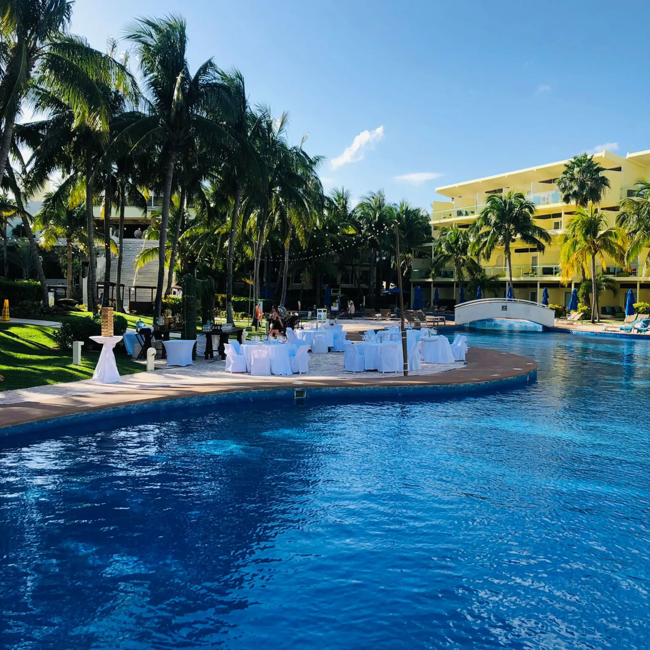 Poolside wedding reception setup with white linens and palm trees at Iberostar Selection Riviera Cancun