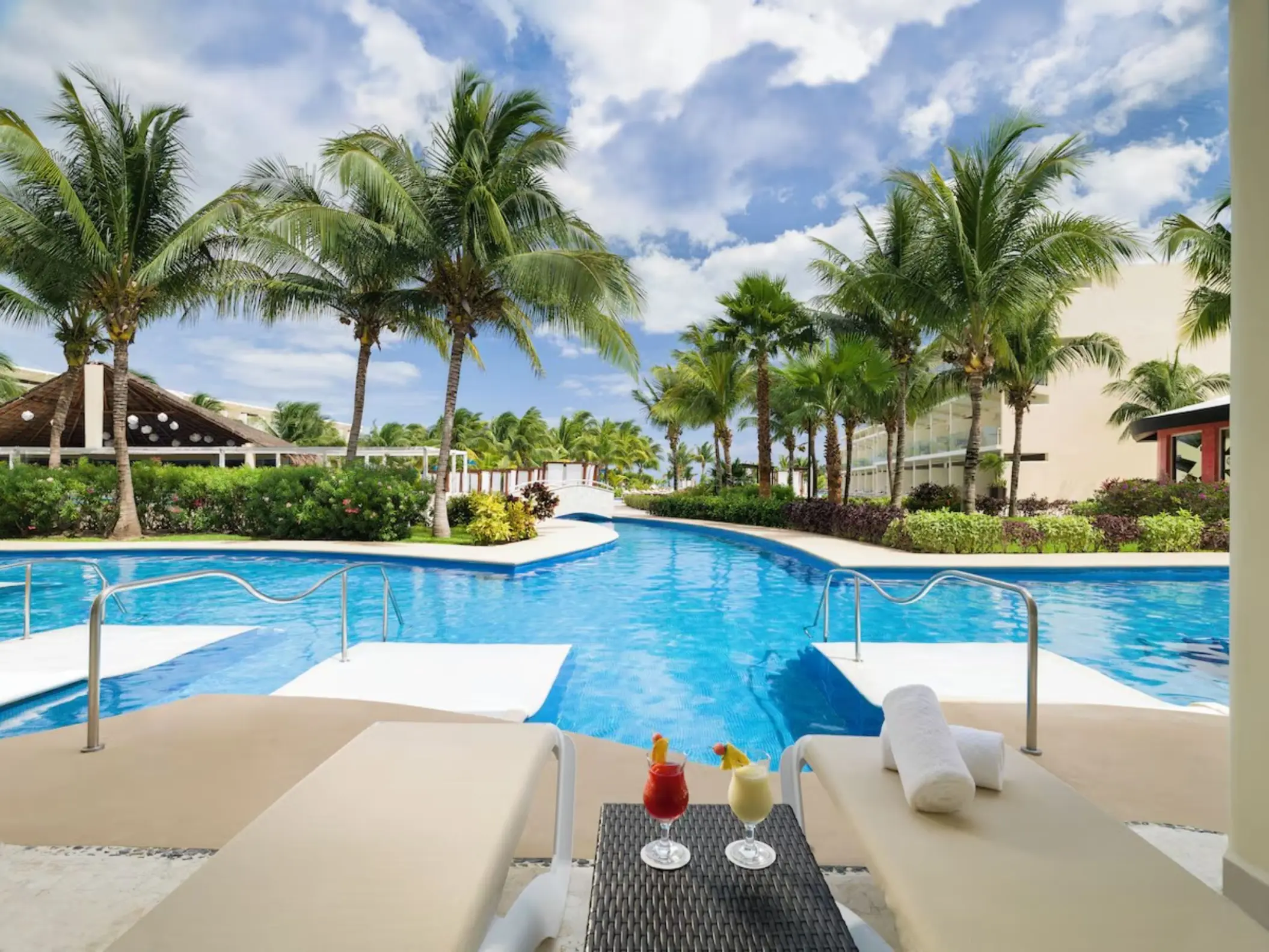 Iberostar Selection Riviera Cancun swimming pool with lounge chairs, tropical cocktails, and palm trees, Cancun