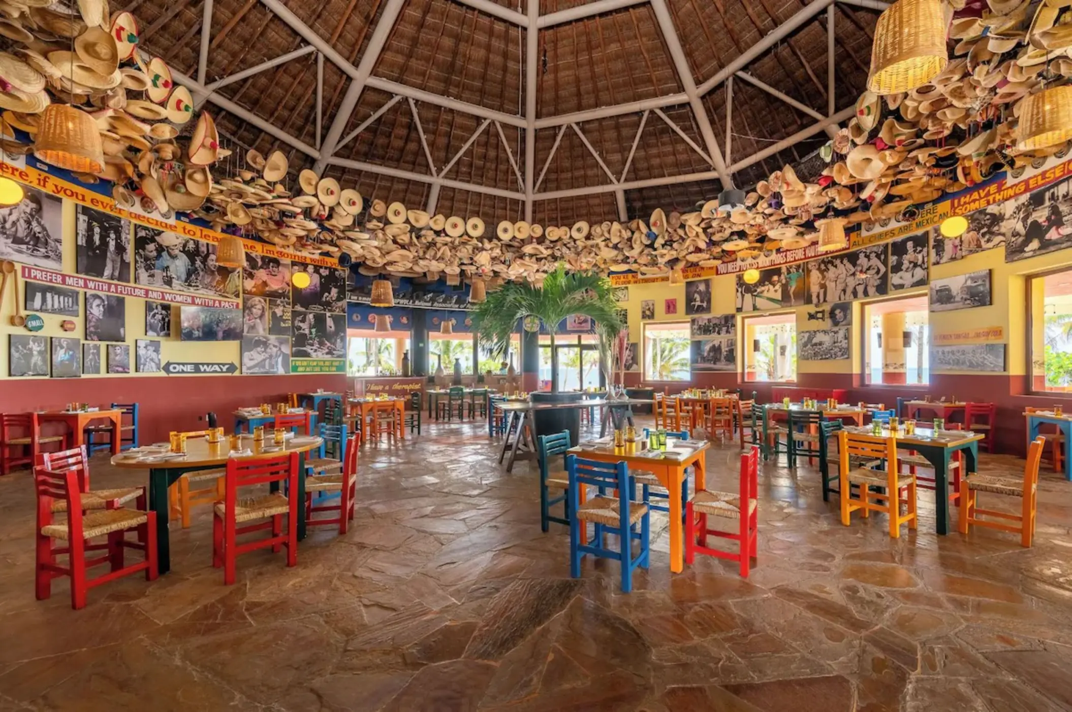 Mexican restaurant with colorful wooden chairs and sombreros hanging from a thatched roof at Iberostar Selection Cancun