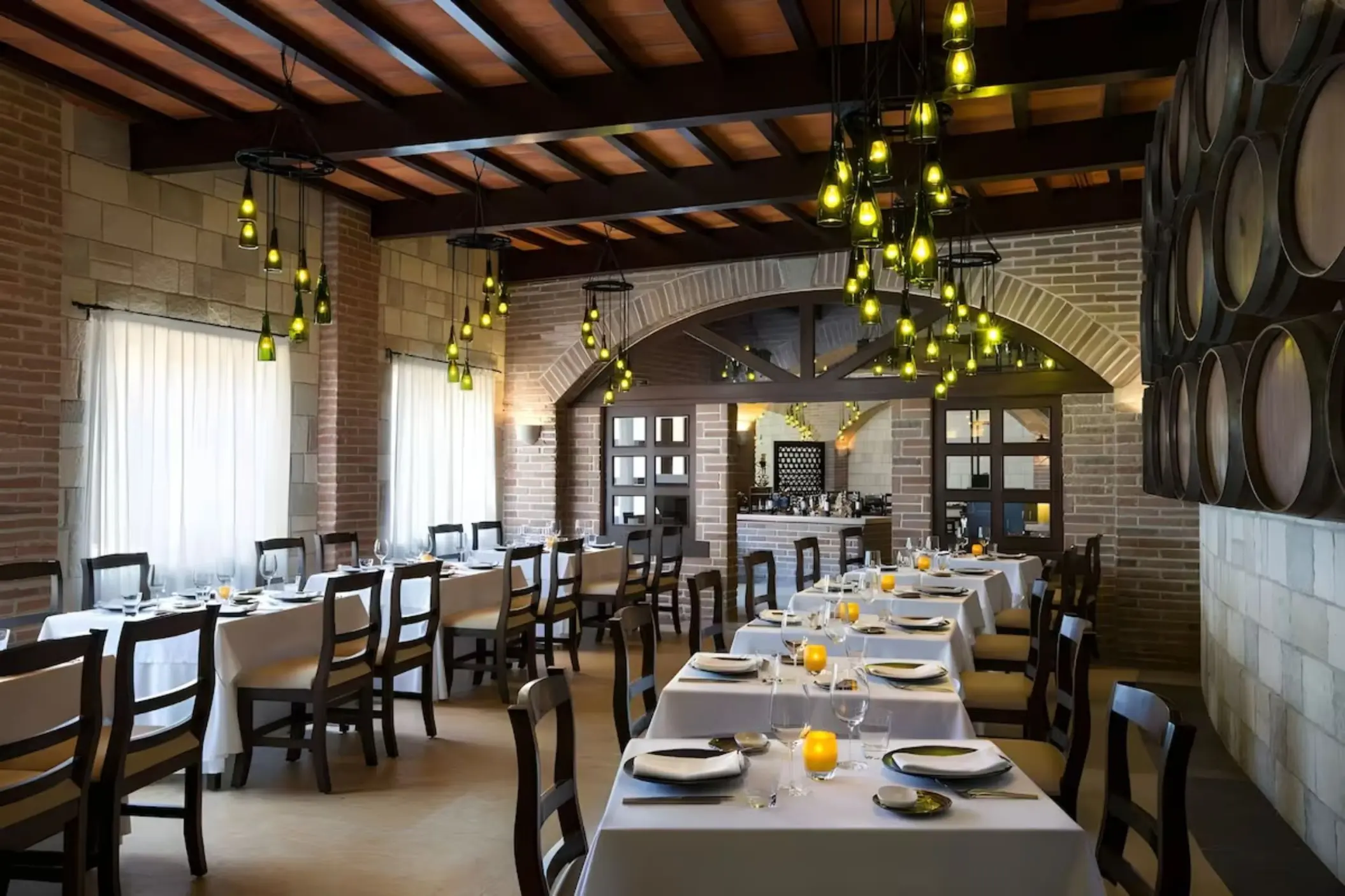 Indoor restaurant with brick walls, wine barrel decor, and hanging bottle lights at Iberostar Selection Riviera Cancun
