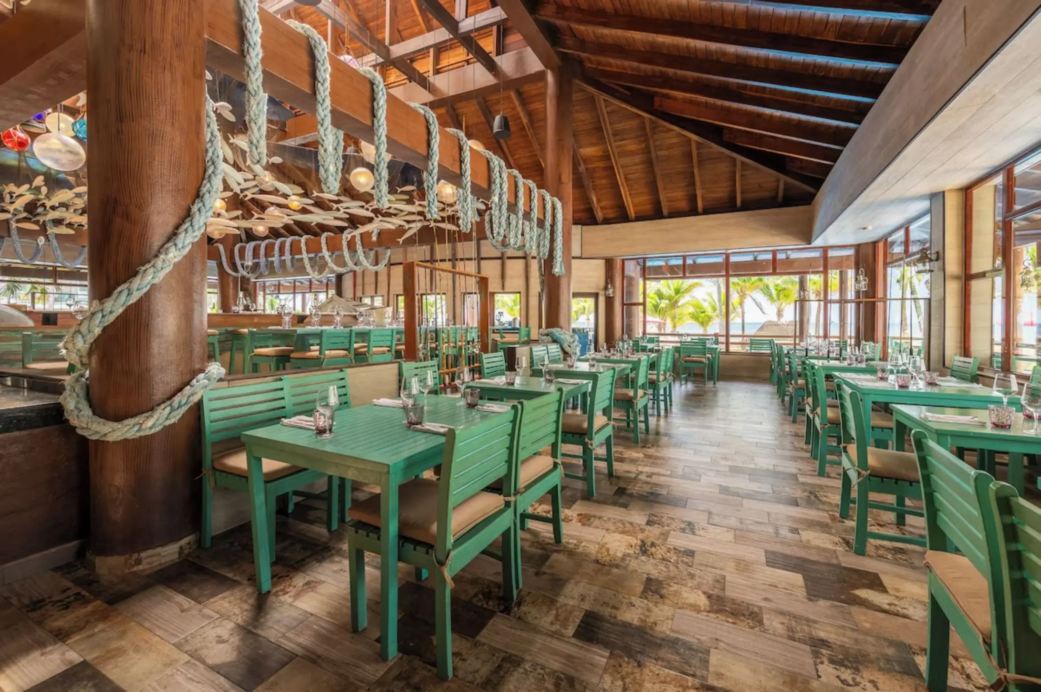 Indoor restaurant with green wooden tables and high ceilings at Iberostar Selection Riviera Cancun, Cancun