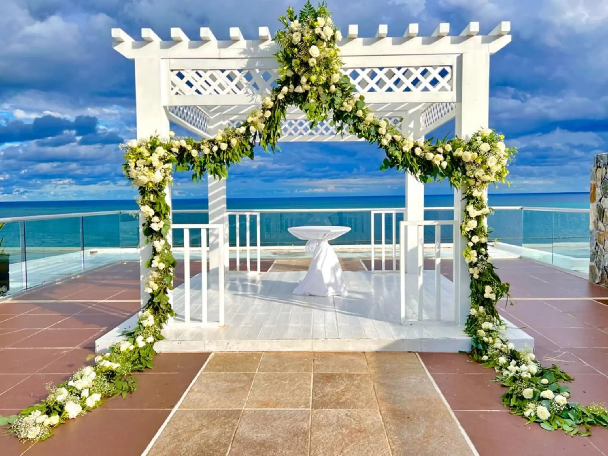 White pergola wedding ceremony setup with floral garlands at Iberostar Selection Riviera Cancun, Cancun