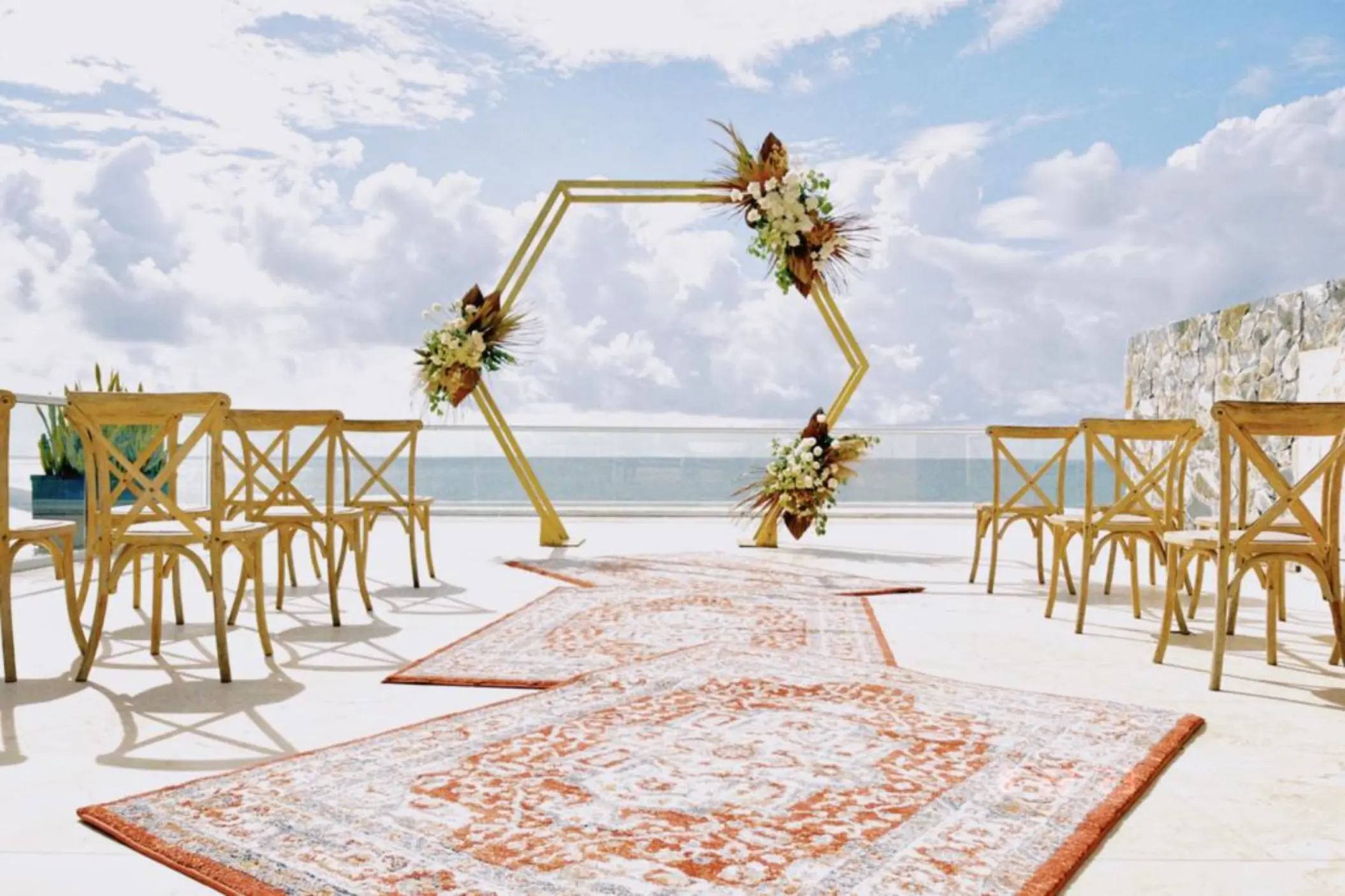 Hexagonal arch and wooden chairs for a rooftop wedding ceremony at Iberostar Selection Riviera Cancun