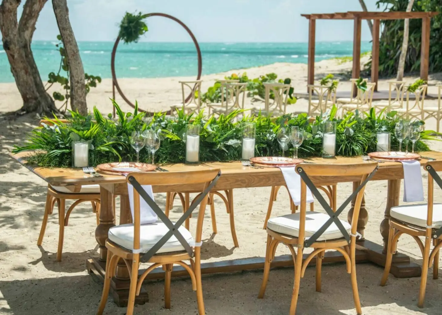 Beachfront wedding reception setup with wooden farm table and cross-back chairs at Iberostar Waves Costa Dorada, Puerto Plata