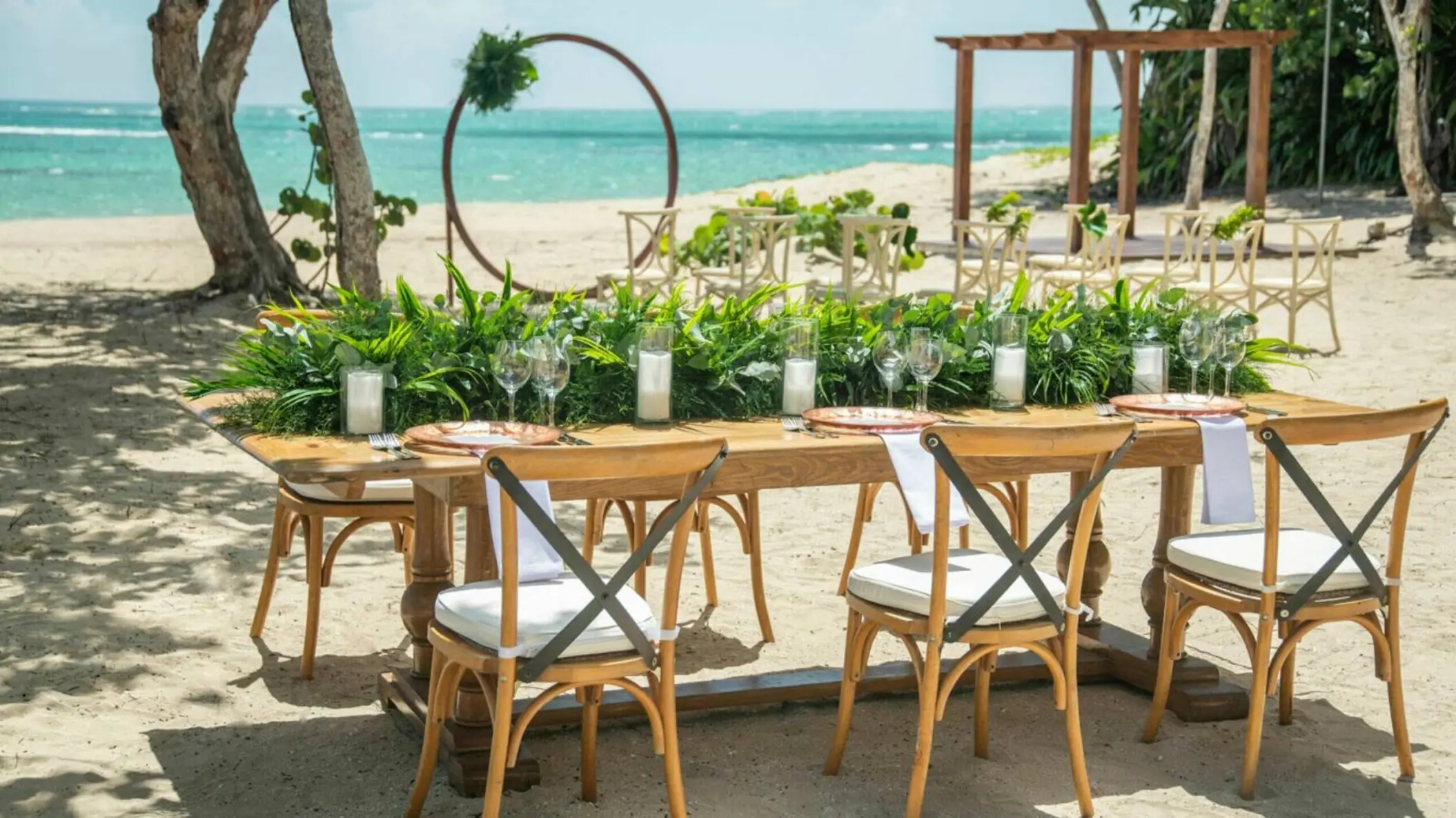 Beachfront wedding reception setup with wooden farm table and cross-back chairs at Iberostar Waves Costa Dorada, Puerto Plata