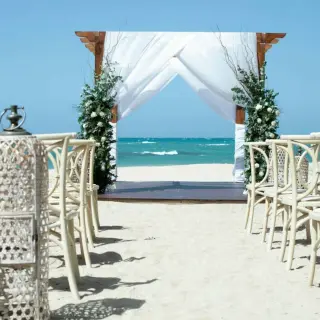 Beachfront wedding ceremony with white fabric arch and lanterns at Iberostar Waves Costa Dorada, Puerto Plata