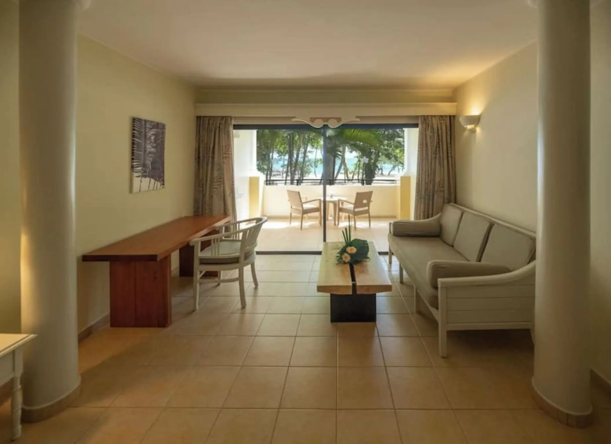 Living area of a suite with a balcony overlooking tropical greenery at Iberostar Waves Costa Dorada, Puerto Plata
