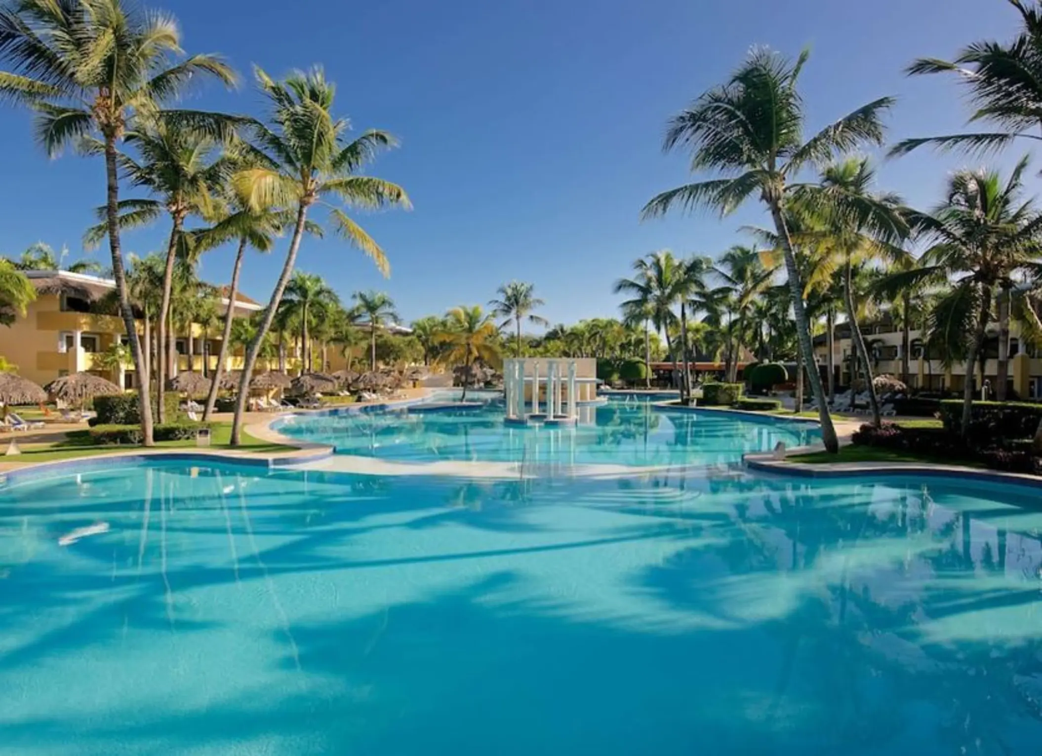 Large swimming pool surrounded by palm trees and tropical gardens at Iberostar Costa Dorada, Puerto Plata