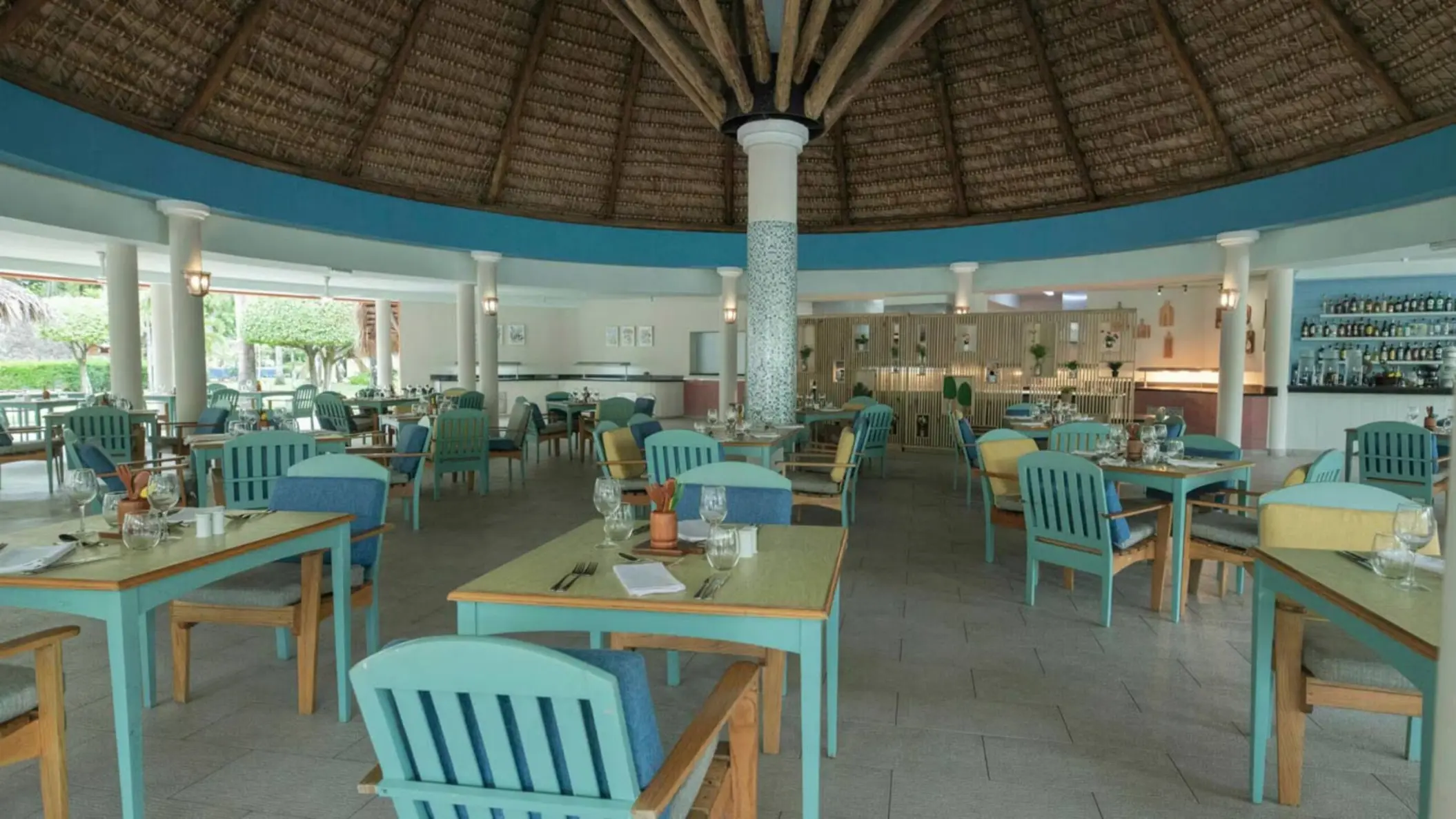 Iberostar Waves Costa Dorada open-air restaurant with blue chairs and a thatched palapa roof, Puerto Plata