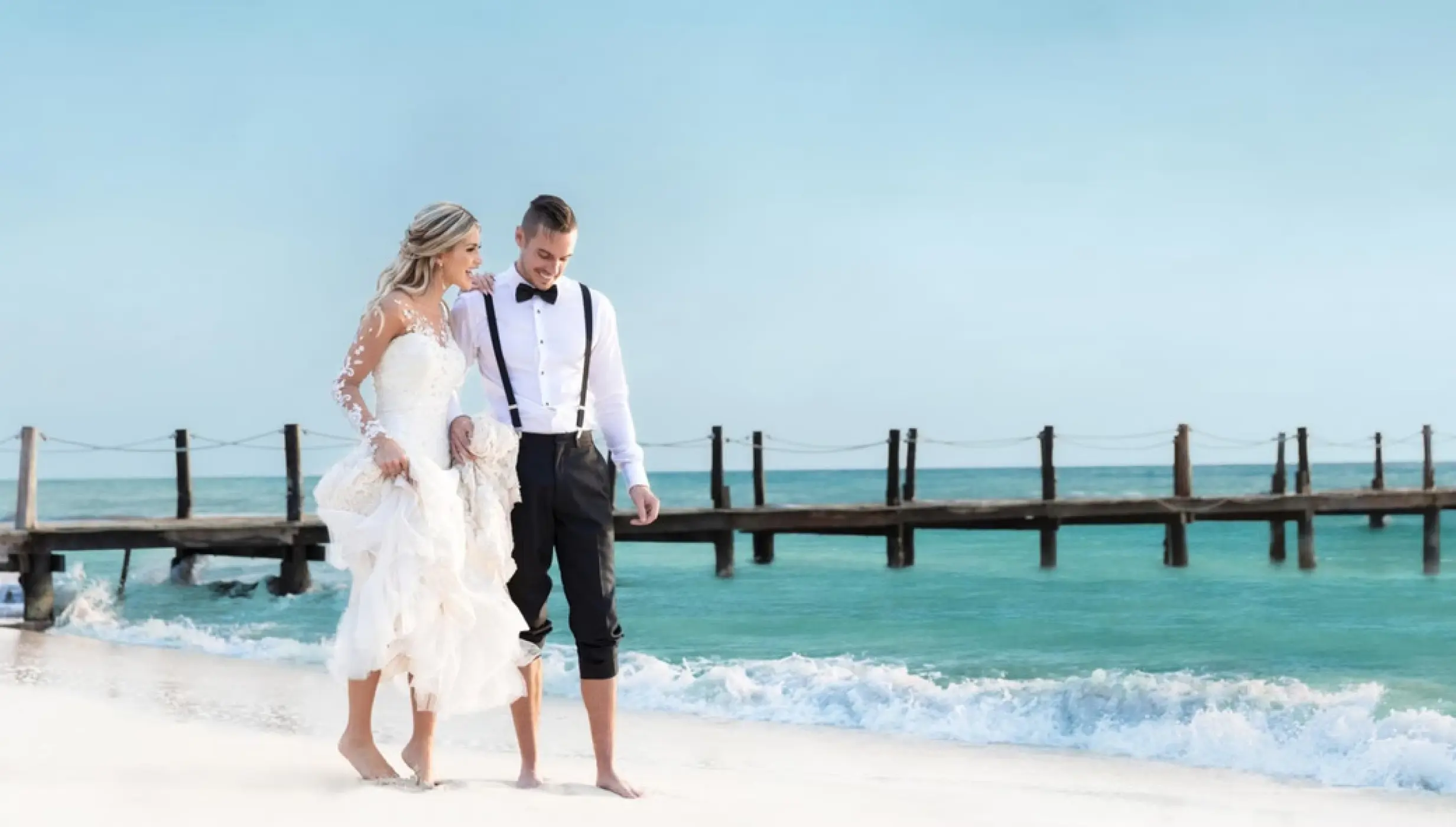Bride and groom walking barefoot along the beach at Iberostar Waves Cozumel