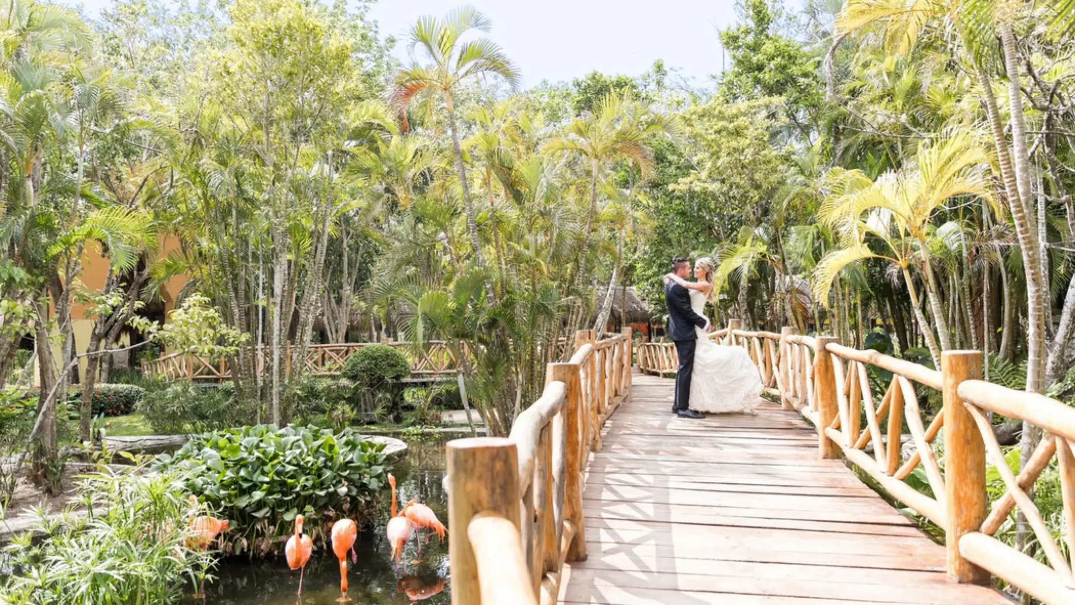 Bride and groom embracing on a wooden bridge at Iberostar Waves Cozumel