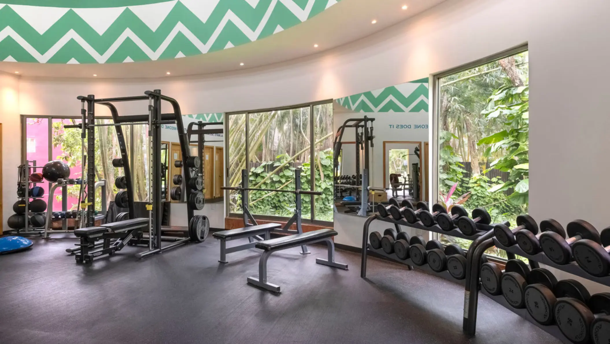 Weight room with dumbbells and squat racks at Iberostar Waves Cozumel