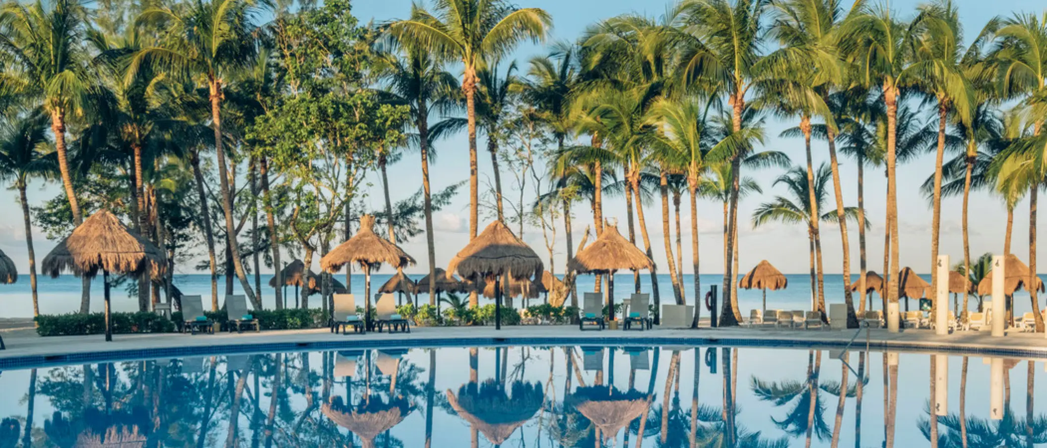 Iberostar Waves Cozumel outdoor swimming pool with thatched umbrellas and palm trees, Cozumel