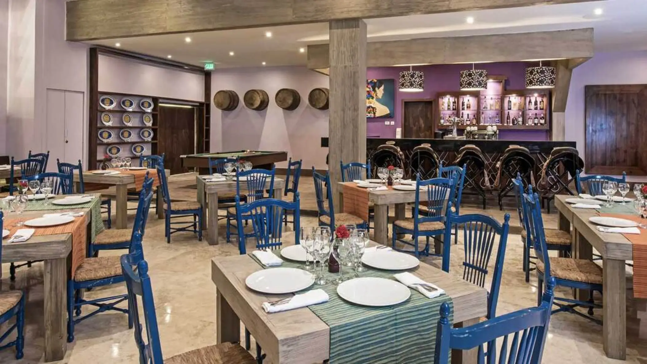 Indoor restaurant dining area with blue wooden chairs and rustic tables at Iberostar Waves Cozumel