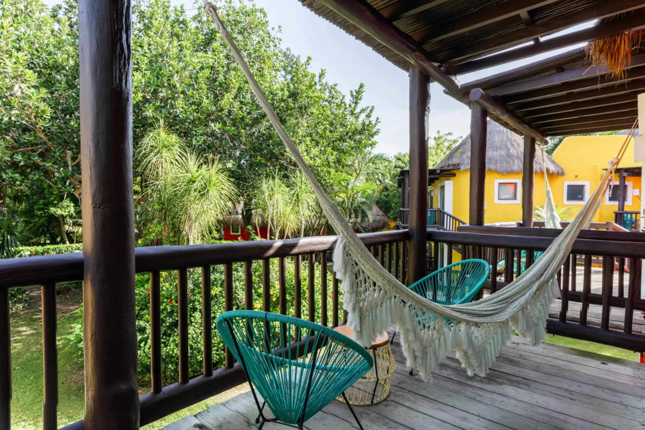 Private suite balcony with white fringe hammock and turquoise chairs at Iberostar Waves Cozumel