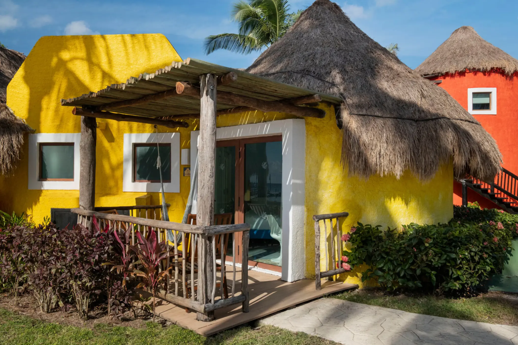 Iberostar Cozumel suite exterior with a thatched roof and yellow walls, Cozumel
