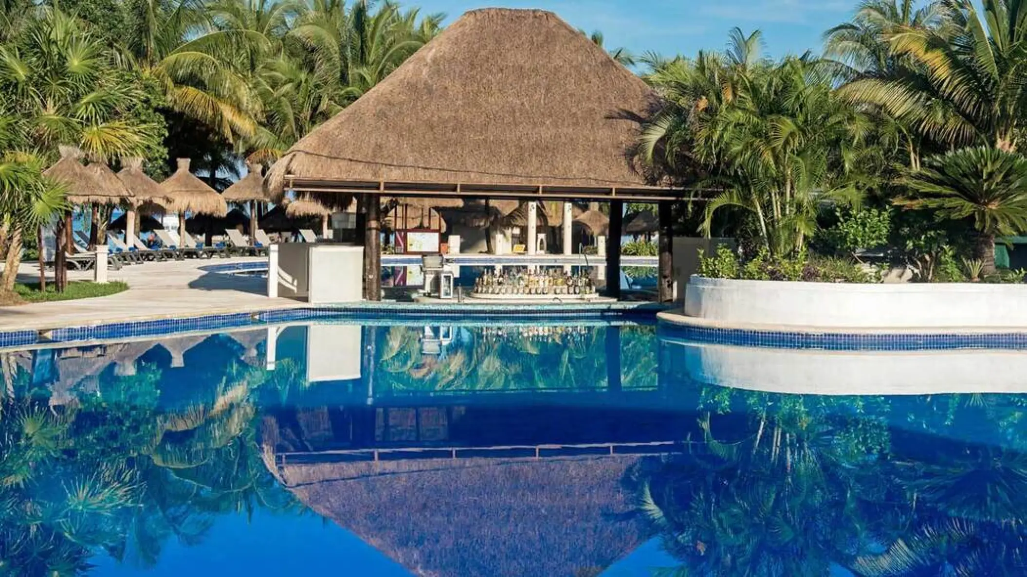 Swim-up bar with a thatched palapa roof at Iberostar Waves Cozumel