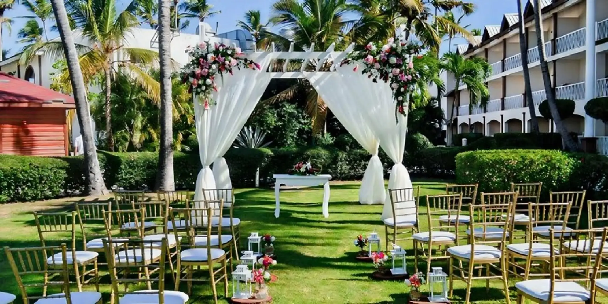 Garden wedding ceremony with white draped pergola and gold chairs at Iberostar Waves Dominicana, Punta Cana