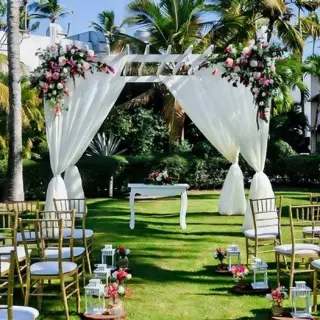 Garden wedding ceremony with white draped pergola and gold chairs at Iberostar Waves Dominicana, Punta Cana
