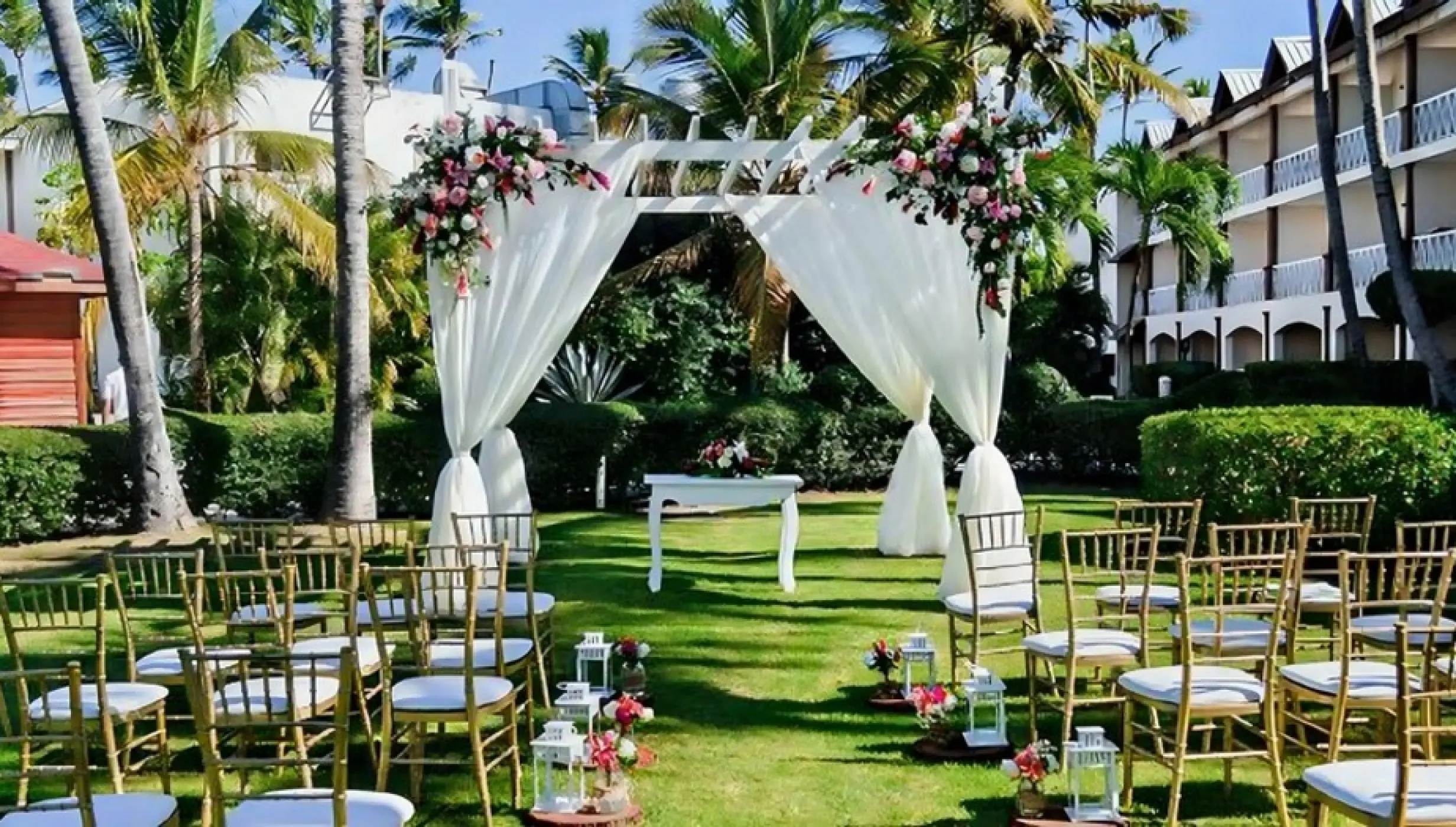 Garden wedding ceremony with white draped pergola and gold chairs at Iberostar Waves Dominicana, Punta Cana