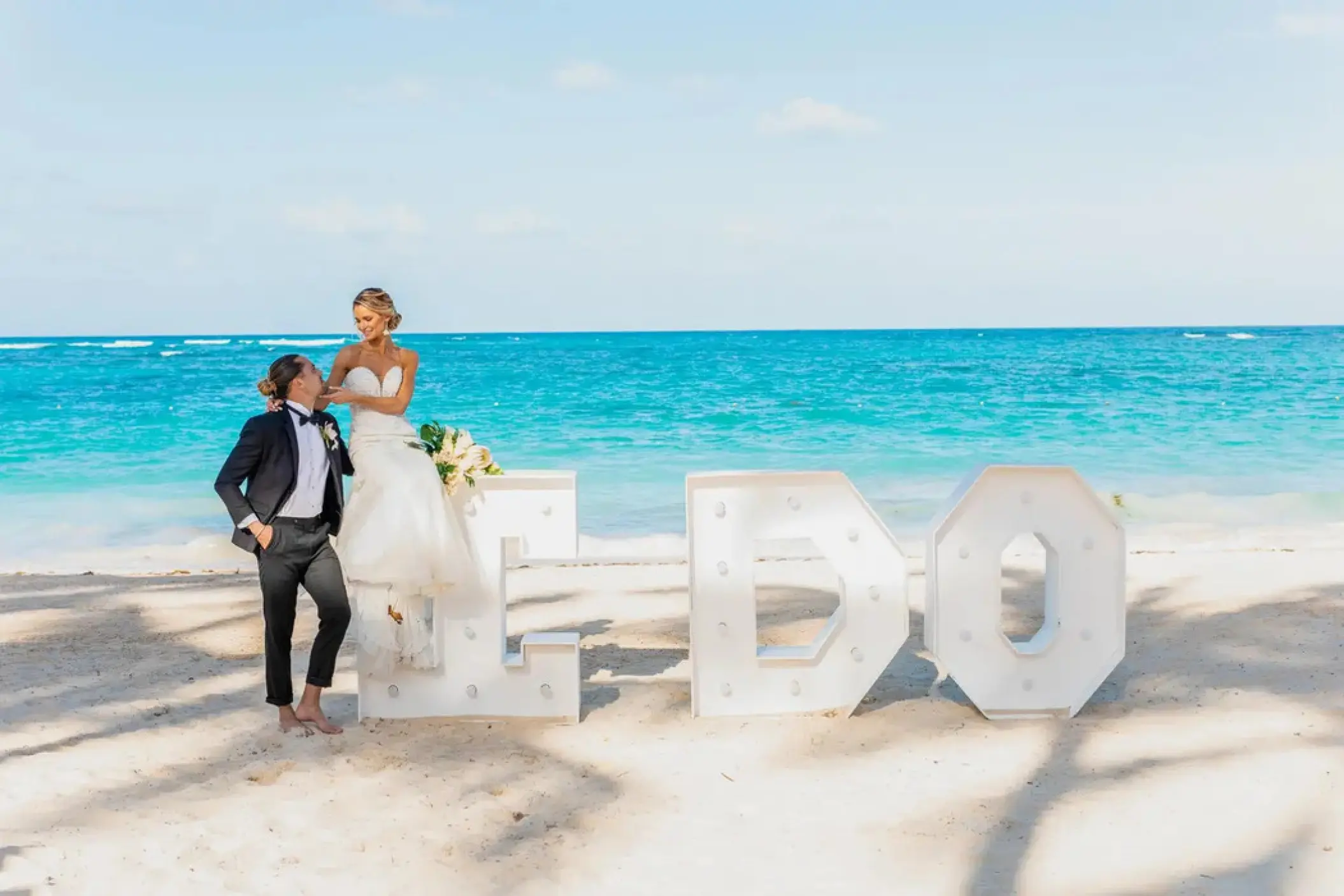 Bride and groom posing with large I DO letters on the beach at Iberostar Rose Hall Beach, Montego Bay