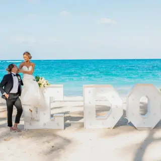 Bride and groom posing with large I DO letters on the beach at Iberostar Rose Hall Beach, Montego Bay