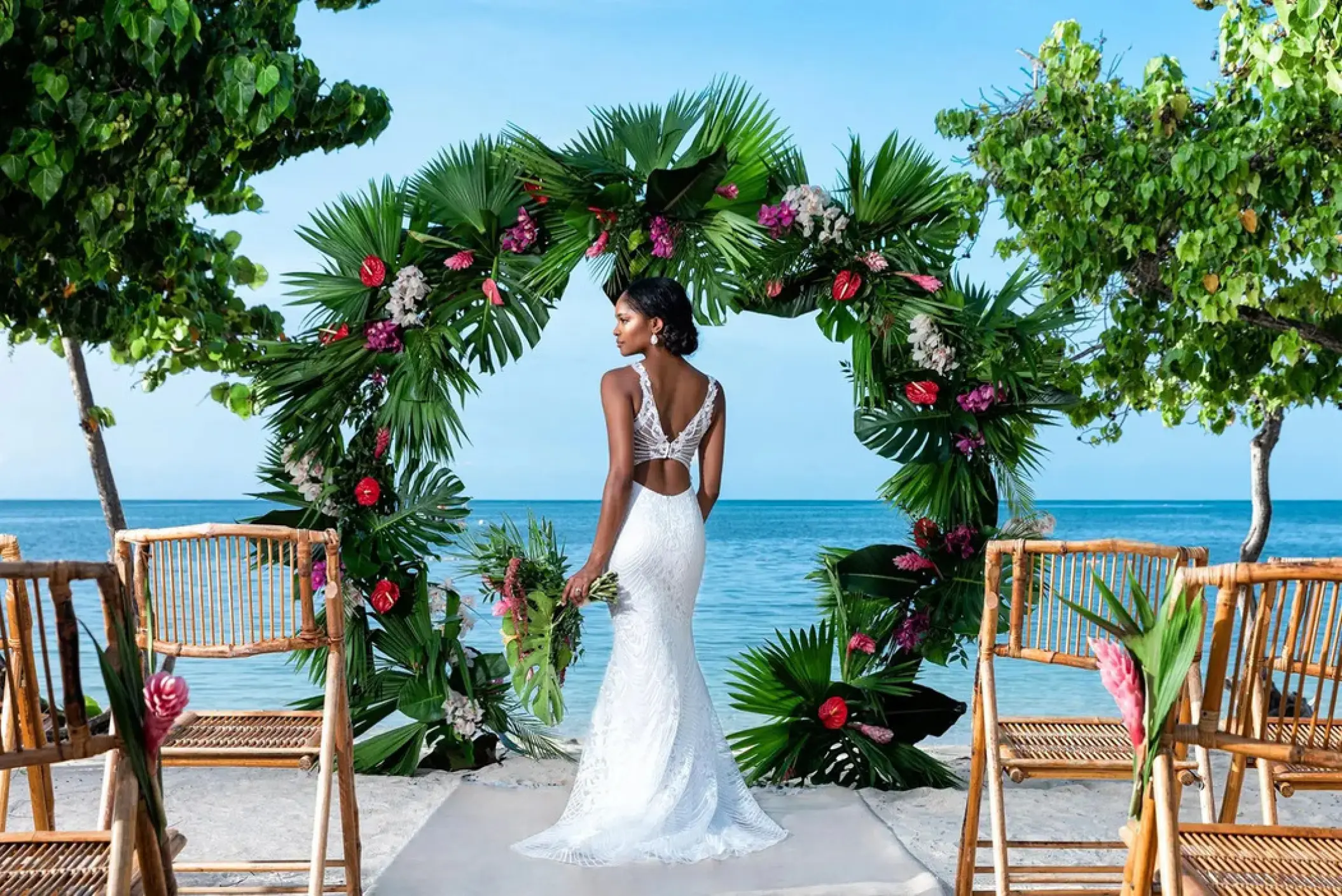 Bride standing before a circular palm leaf wedding arch at Iberostar Rose Hall Beach, Montego Bay