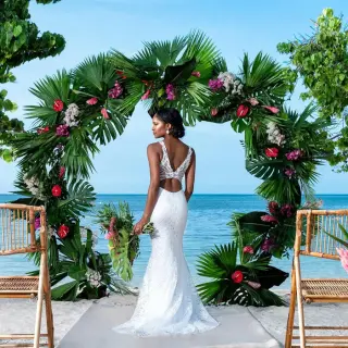 Bride standing before a circular palm leaf wedding arch at Iberostar Rose Hall Beach, Montego Bay