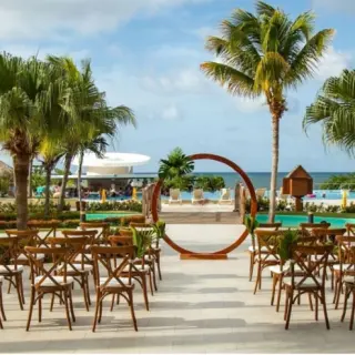 Outdoor wedding ceremony with a circular arch and wooden chairs at Iberostar Waves Rose Hall Beach, Montego Bay