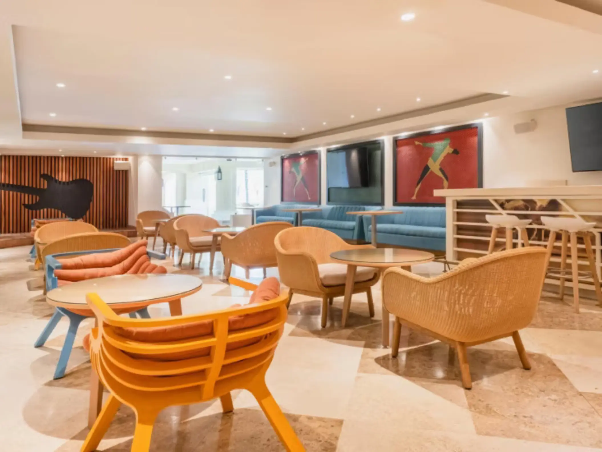 Indoor lounge area with colorful wicker chairs and a guitar silhouette at Iberostar Rose Hall Beach, Montego Bay