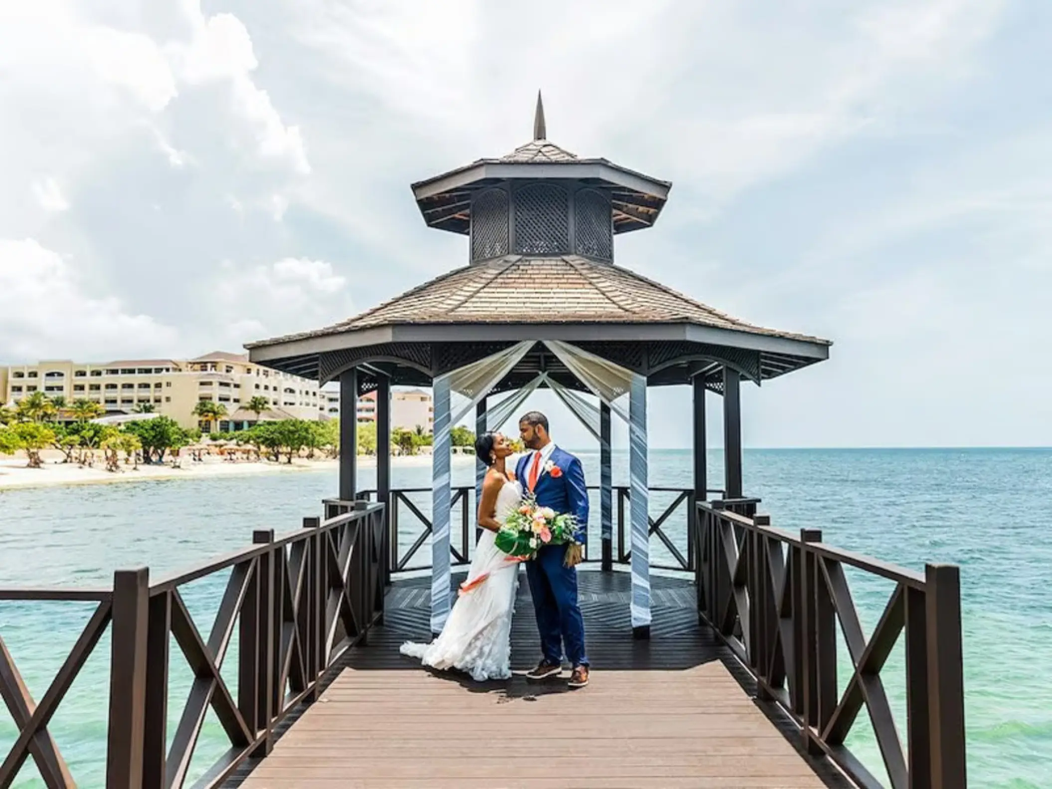 The couple posing under the pier gazebo during a wedding at Iberostar Rose Hall Beach, Montego Bay