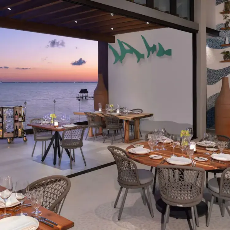 Spezia Restaurant open-air dining tables overlooking the ocean at sunset, Impression Isla Mujeres