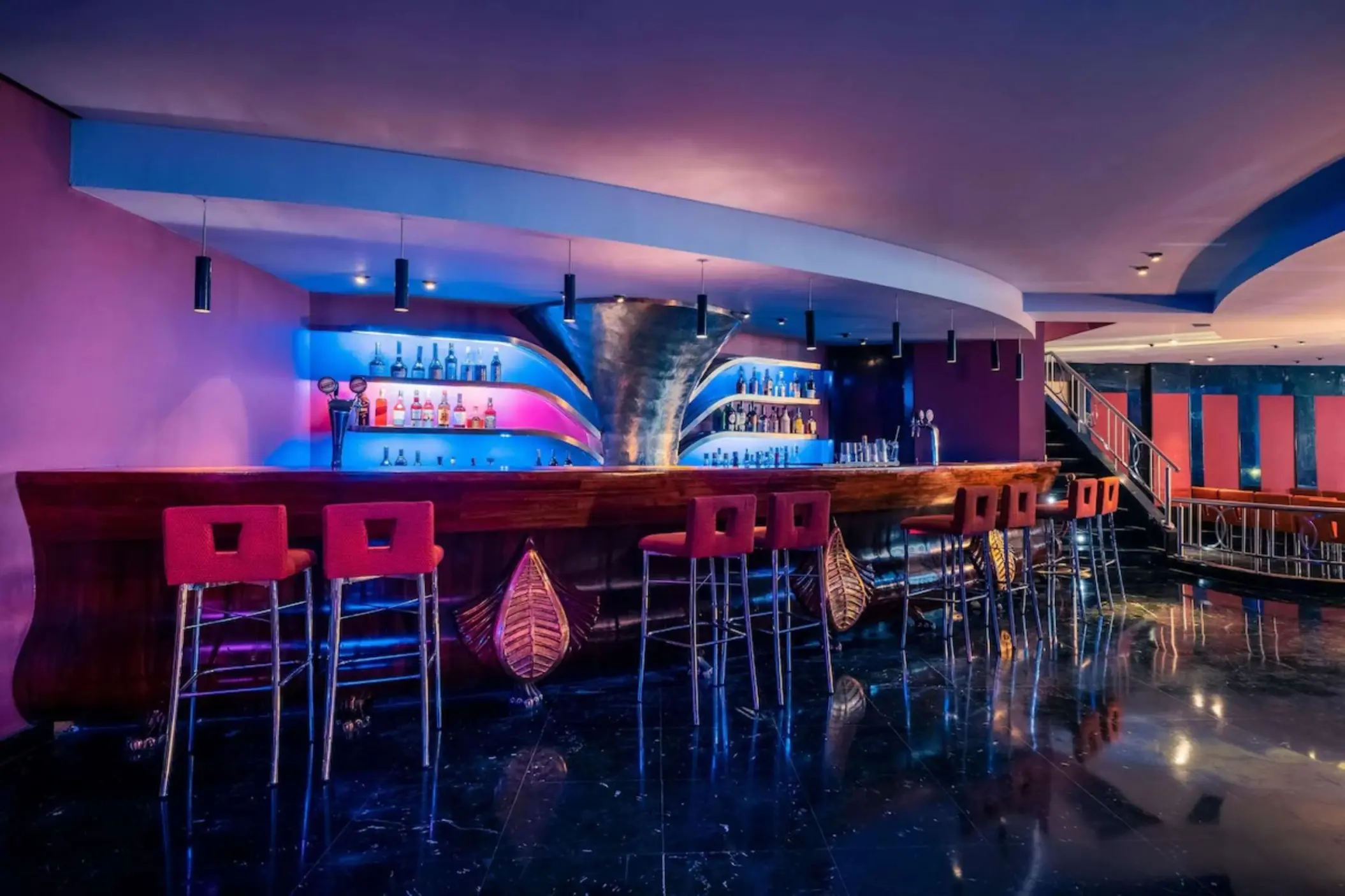 Modern indoor bar with pink and blue neon lighting at JOIA Rose Hall, Montego Bay