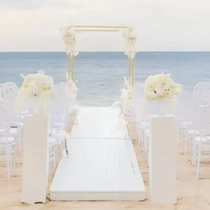 Beachfront wedding ceremony with white chairs and floral arch at JOIA Rose Hall by Iberostar, Montego Bay