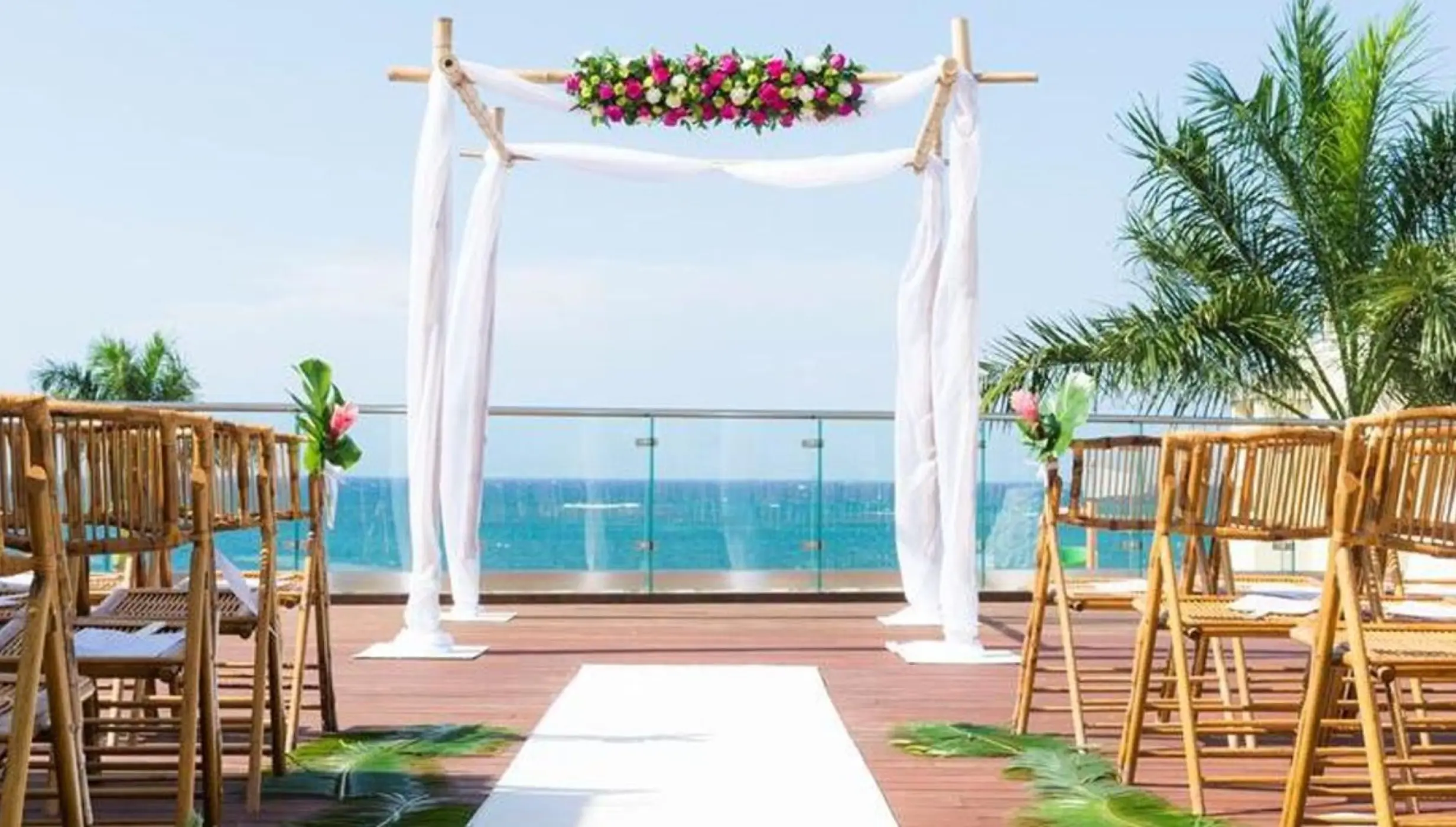 Sky deck wedding ceremony with bamboo chairs and floral arch at JOIA Rose Hall, Montego Bay
