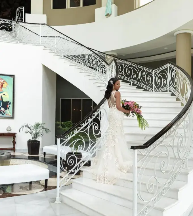 Bride holding a bouquet on the white grand staircase at JOIA Rose Hall by Iberostar, Montego Bay