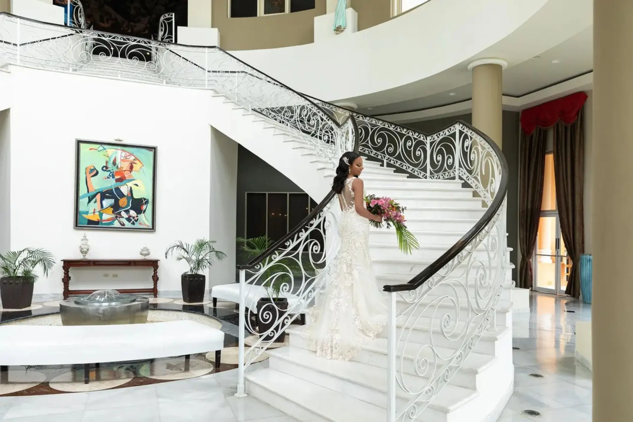 Bride holding a bouquet on the white grand staircase at JOIA Rose Hall by Iberostar, Montego Bay