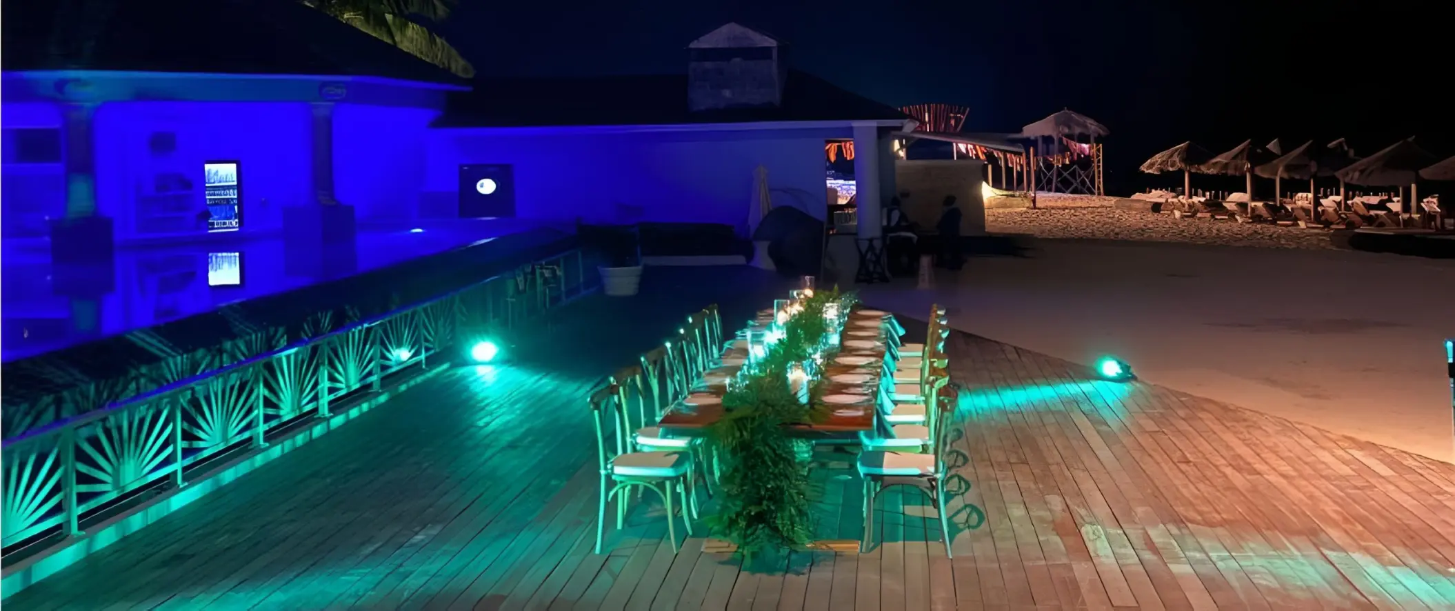 Long wooden dining table with green lighting at JOIA Rose Hall by Iberostar, Montego Bay