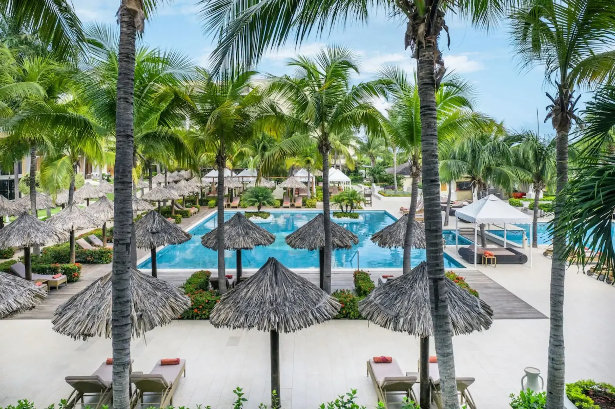 JOIA Rose Hall pool area with palm trees and thatched umbrellas, Montego Bay