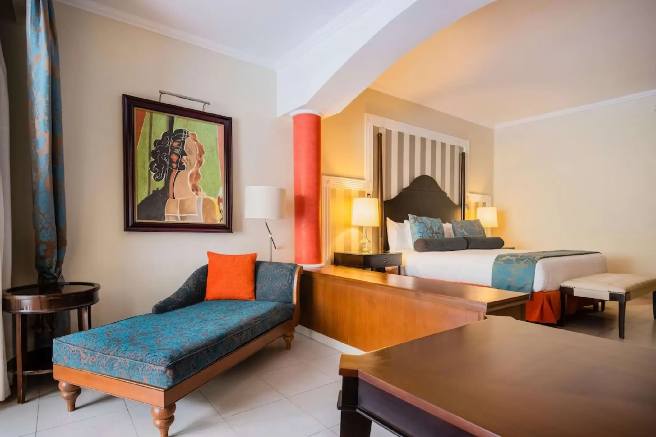 Guest suite with blue chaise lounge and king bed at JOIA Rose Hall, Montego Bay
