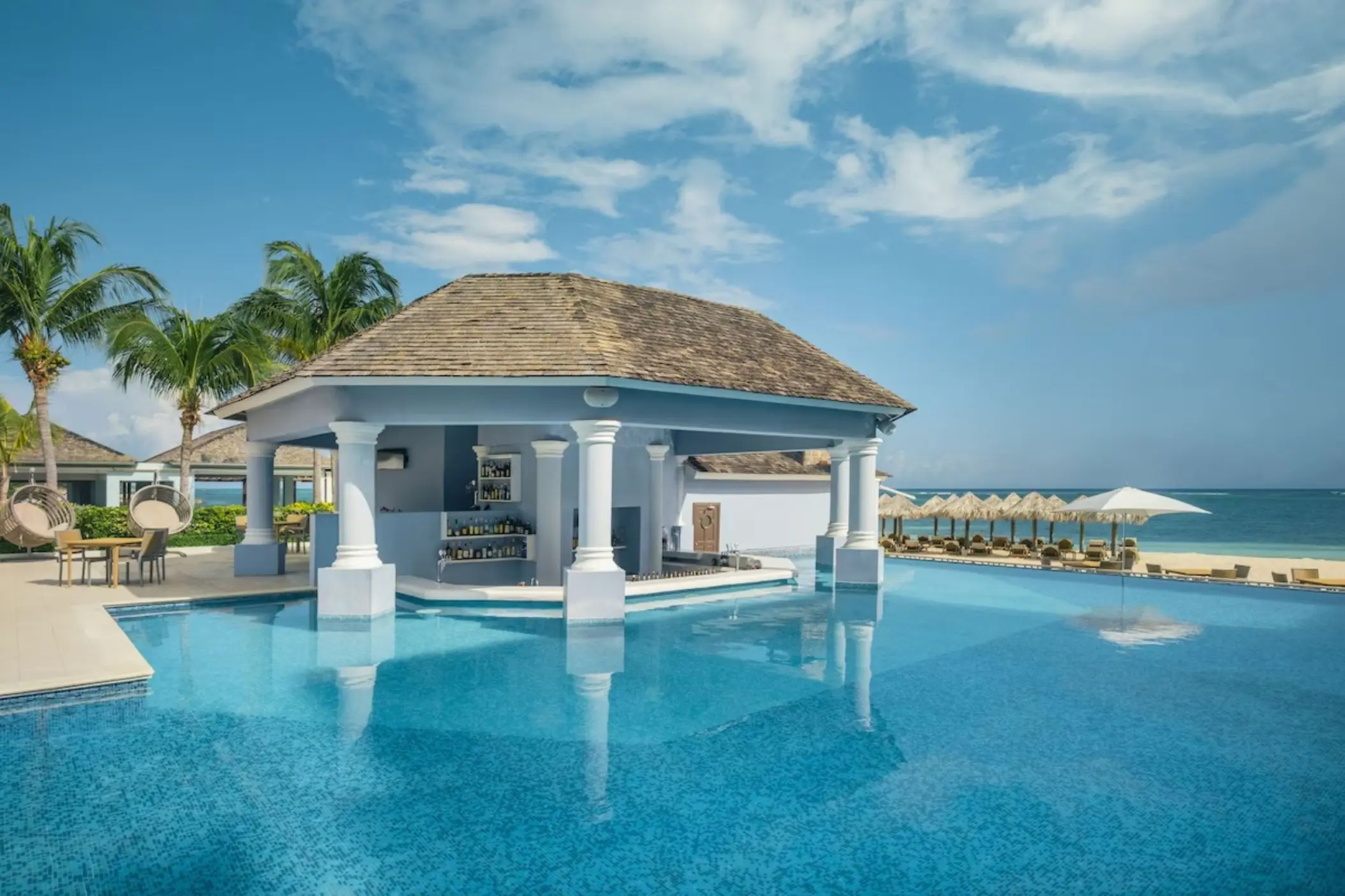 Swim-up bar with white columns and thatched roof at JOIA Rose Hall by Iberostar, Montego Bay