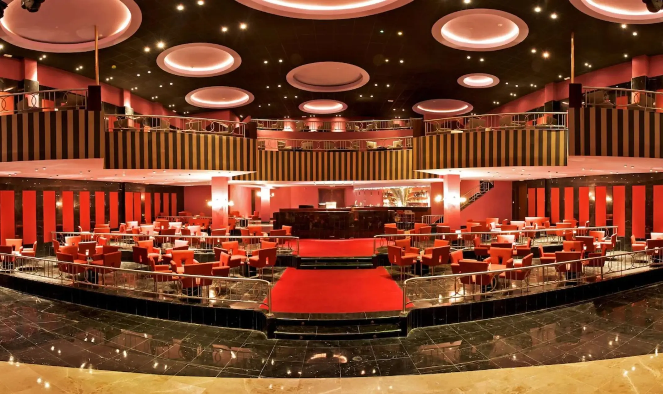Theater restaurant with red seating and circular ceiling lights at JOIA Rose Hall by Iberostar, Montego Bay