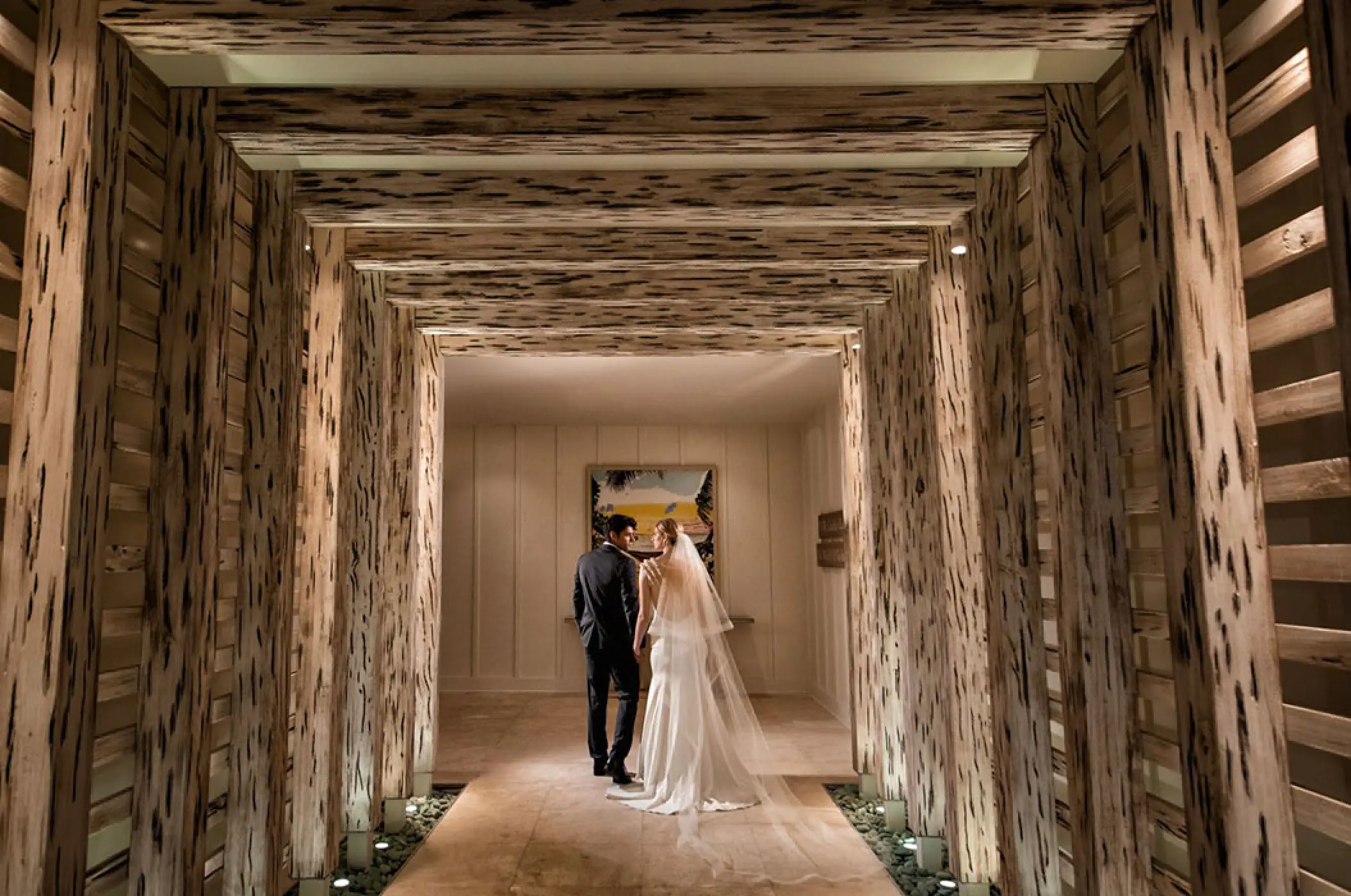The bride and groom walking through a wooden architectural hallway at Margaritaville Island Reserve Cap Cana, Punta Cana
