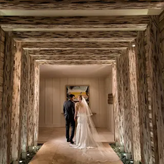 The bride and groom walking through a wooden architectural hallway at Margaritaville Island Reserve Cap Cana, Punta Cana