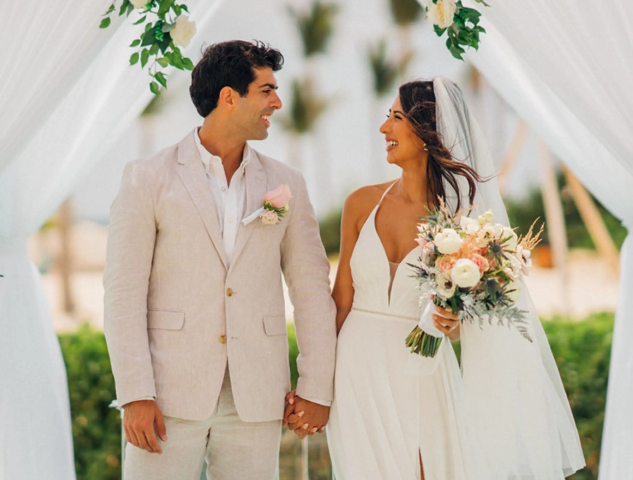 Bride and groom holding hands under a white gazebo at Margaritaville Island Reserve Cap Cana, Punta Cana