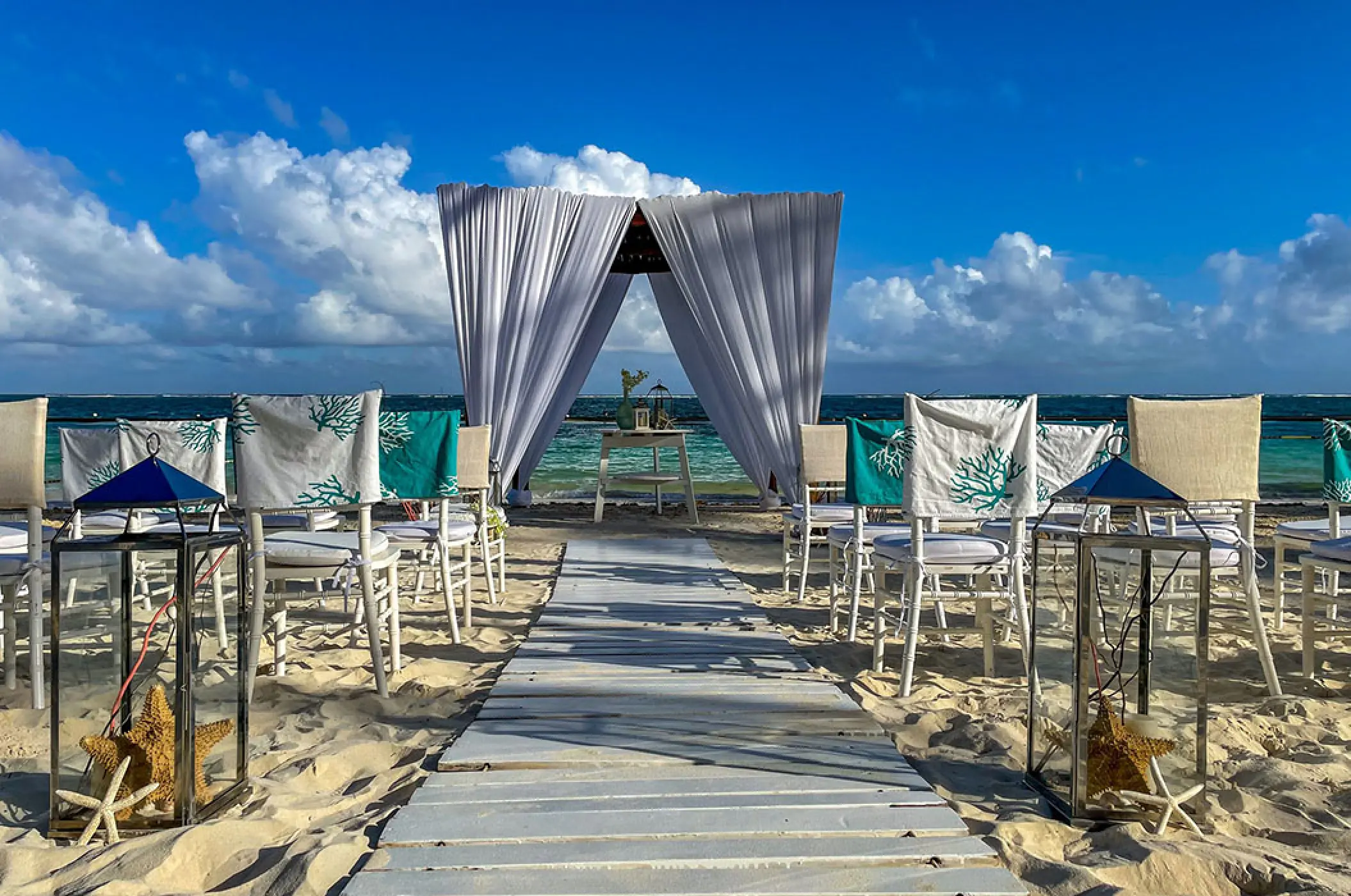 Beachfront wedding ceremony setup with white draped gazebo and starfish decor at Margaritaville Island Reserve Cap Cana