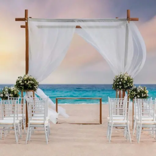 Beachfront wedding ceremony setup with a white draped gazebo and white chairs at Le Blanc Spa Resort, Cancun