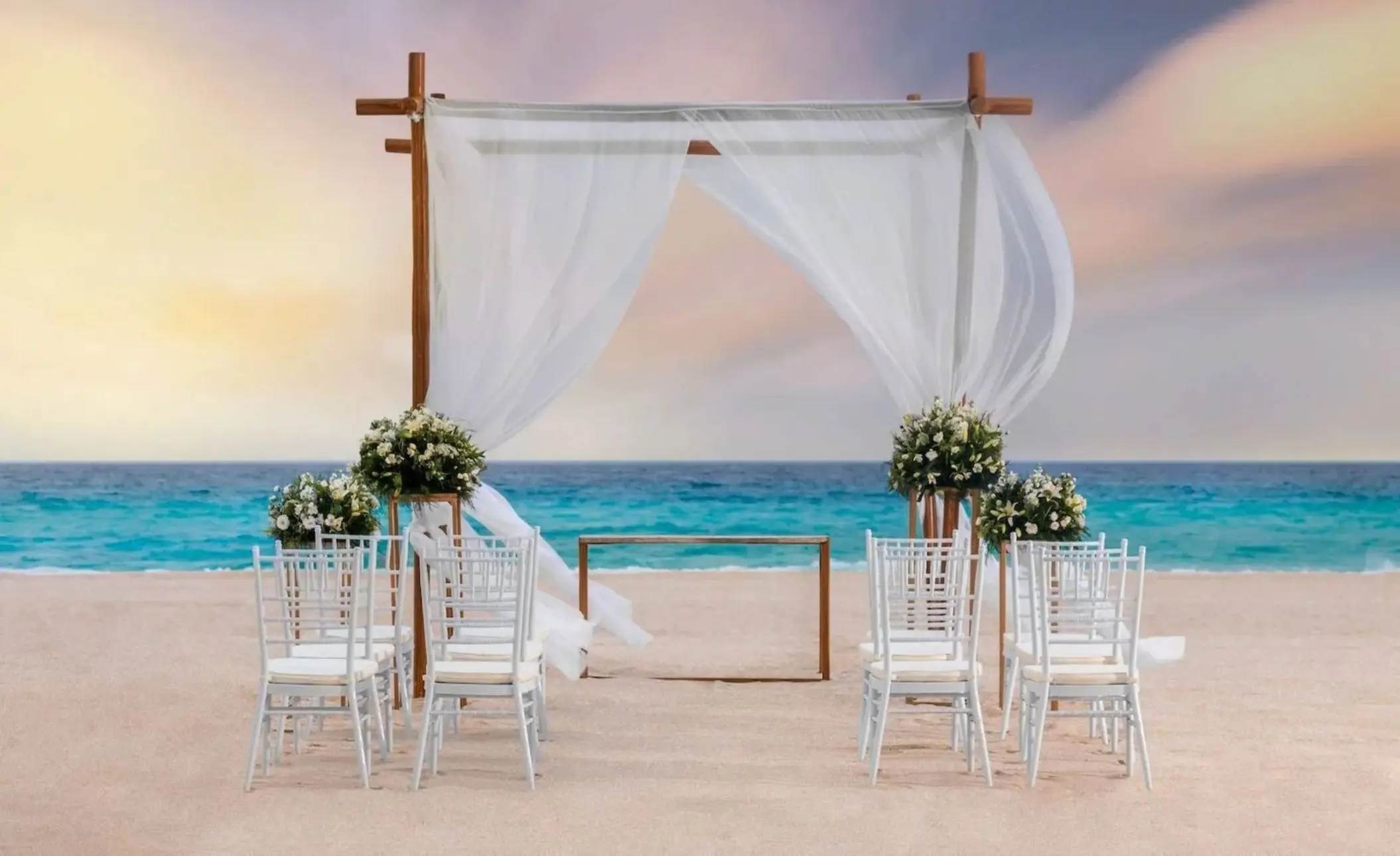 Beachfront wedding ceremony setup with a white draped gazebo and white chairs at Le Blanc Spa Resort, Cancun